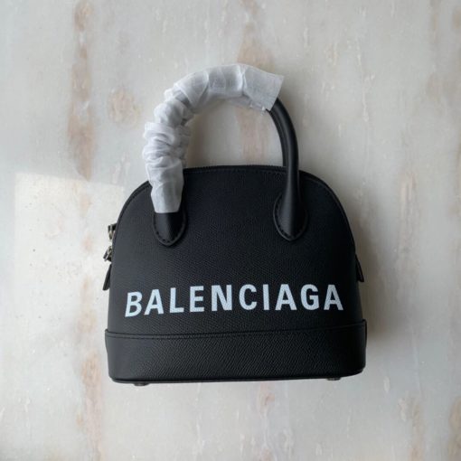 BALENCIAGA Mini Ville Logo Leather Bag. Original Quality Bag. Authentic Epi leather. Metal Toned Hardware. BALENCIAGA Sales Box and Dust Bag. Authenticity Card. BALENCIAGA's Ville mini bowling bag is crafted of grained calfskin printed with a large statement logo at the front and back. This design works as a zipped-top construction with a padlock charm to ensure your valuables are securely stowed. The versatile style can be carried by its rolled handles or over the shoulder via a detachable flat strap. | CRIS&COCO Authentic Quality Designer Bags and Luxury Accessories