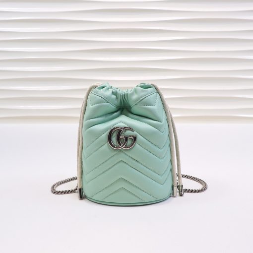 GUCCI GG Marmont Mini Bucket Bag. Original Quality Bag including gift box, literature, dust bag, authenticity card. The world of GG Marmont expands with the introduction of a mini bucket bag shape crafted from Matelassé leather in vibrant tones. Inspired by an archival design from the '70s, a hallmark era of the House, the Double G decorates the front of this accessory. Featuring a chain strap and drawstring closure the versatile shape can be worn as shoulder and as a crossbody bag. | Cris and Coco. High Quality Bags and Luxury Accessories