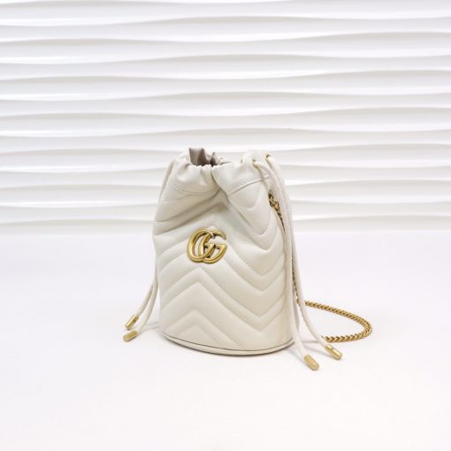 GUCCI GG Marmont Mini Bucket Bag. Original Quality Bag including gift box, literature, dust bag, authenticity card. The world of GG Marmont expands with the introduction of a mini bucket bag shape crafted from Matelassé leather in vibrant tones. Inspired by an archival design from the '70s, a hallmark era of the House, the Double G decorates the front of this accessory. Featuring a chain strap and drawstring closure the versatile shape can be worn as shoulder and as a crossbody bag. | Cris and Coco. High Quality Bags and Luxury Accessories