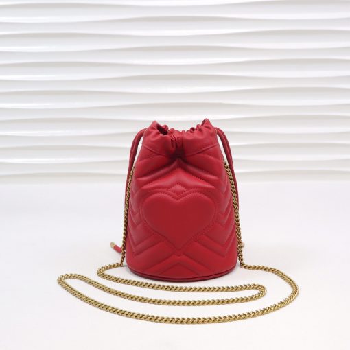 GUCCI GG Marmont Mini Bucket Bag. Original Quality Bag including gift box, literature, dust bag, authenticity card. The world of GG Marmont expands with the introduction of a mini bucket bag shape crafted from Matelassé leather in vibrant tones. Inspired by an archival design from the '70s, a hallmark era of the House, the Double G decorates the front of this accessory. Featuring a chain strap and drawstring closure the versatile shape can be worn as shoulder and as a crossbody bag. | Cris and Coco. High Quality Bags and Luxury Accessories