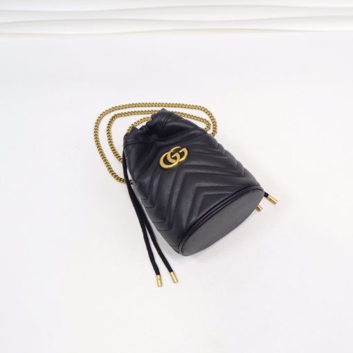 GUCCI GG Marmont Mini Bucket Bag. Original Quality Bag including gift box, literature, dust bag, authenticity card. The world of GG Marmont expands with the introduction of a mini bucket bag shape crafted from Matelassé leather in vibrant tones. Inspired by an archival design from the '70s, a hallmark era of the House, the Double G decorates the front of this accessory. Featuring a chain strap and drawstring closure the versatile shape can be worn as shoulder and as a crossbody bag. | Cris and Coco. High Quality Bags and Luxury Accessories