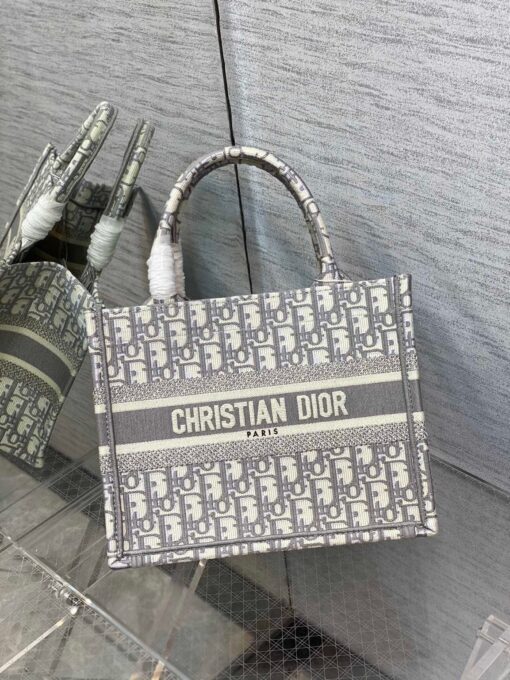 DIOR Small Book Tote. Original Quality Bag including gift box, care book, dust bag, authenticity card. This DIOR Tote is an original creation introduced by Dior's Creative Director, Maria Grazia Chiuri, and has become a staple of the Dior aesthetic. Designed to hold all the daily essentials, it is fully embroidered. Adorned with a Christian Dior Paris signature on the front, the small tote exemplifies the House's signature savoir-faire and may be carried by hand. | CRIS&COCO Authentic Quality Designer Bags and Luxury Accessories