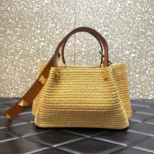 VALENTINO GARAVANI Straw Summer Small Tote.  Original Quality Bag including gift box, literature, dust bag, authenticity card. The Summer tote bag is defined by its woven raffia design and the brass-toned VLogo plaque, the unmistakable symbol of Valentino Garavani. The detachable shoulder strap is adorned with the iconic Roman Studs, another of the brand's signature details. | CRIS AND COCO Authentic Quality Luxury Accessories