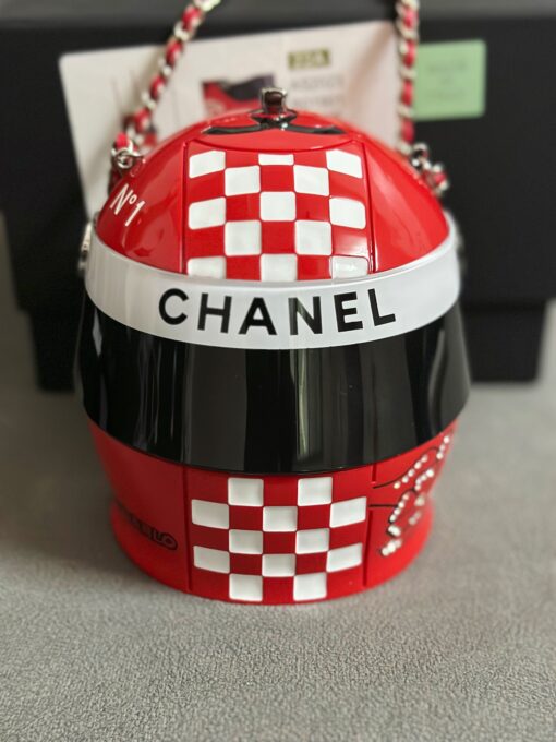 CHANEL Helmet Minaudiere. High-End Quality Bag including gift box, care book, dust bag, authenticity card. This precious creation was unveiled along with the Slot Machine Minaudière and Sphere Minaudière at #CHANELCruise 2023. The 11 cm by 10 cm objet d’art sees diamanté crystals and Chanel logos peppering the full resin exterior for maximum effect. Capturing attention in eye-catching black, red and white, it is equal parts clutch and eye candy. | CRIS AND COCO Authentic Quality Luxury Accessories