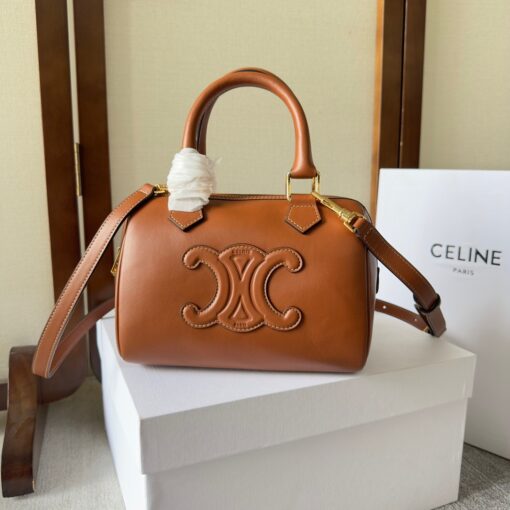 CELINE Small Boston Cuir Triomphe. Style meets sophistication with this timeless Celine Bag. The Celine Small Boston Cuir Triomphe is a classic accessory that is perfect for both day and night. It is made out of smooth calfskin leather with a stitched monogram pattern that creates an elegant, modern look. The bag features a removable and adjustable shoulder strap, a top handle for carrying, and a zipped closure. It also has a main spacious compartment, and one inner flat pocket. It has a small and compact size, perfect for days when you don't want to carry too much. The timeless design will never go out of style, and you'll be sure to feel confident and stylish with this bag on your arm. | CRIS AND COCO Authentic Quality Luxury Accessories