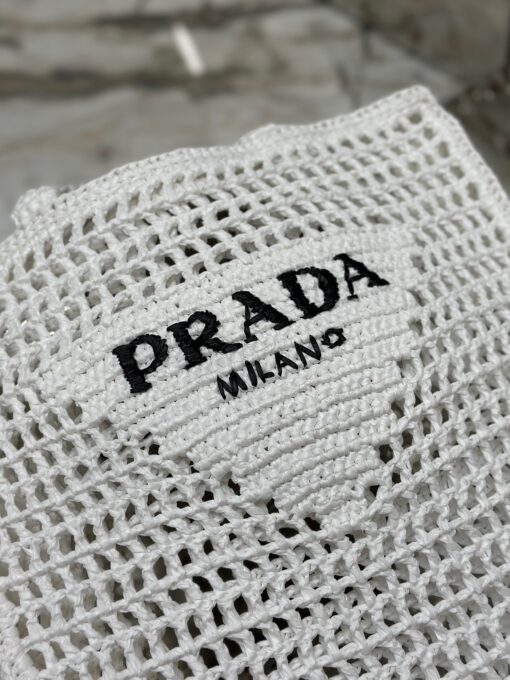 PRADA Crochet Tote Bag. Elevate your style with Prada's signature tote bag. This tote bag is the perfect addition to any summer wardrobe! Adorned with Prada's iconic triangle logo and embroidered lettering, its soft, deconstructed design is made with a light and natural raffia-effect yarn. It's sure to add an elevated touch to your ensemble. | CRIS&COCO Authentic Quality Designer Bags and Luxury Accessories