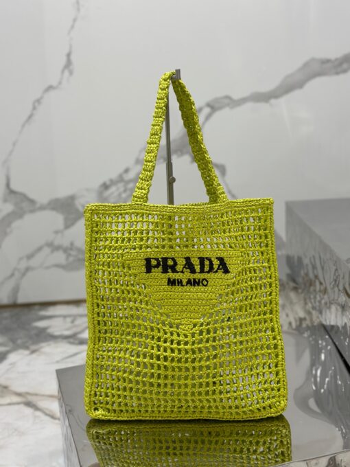 PRADA Crochet Tote Bag. Elevate your style with Prada's signature tote bag. This tote bag is the perfect addition to any summer wardrobe! Adorned with Prada's iconic triangle logo and embroidered lettering, its soft, deconstructed design is made with a light and natural raffia-effect yarn. It's sure to add an elevated touch to your ensemble. | CRIS&COCO Authentic Quality Designer Bags and Luxury Accessories