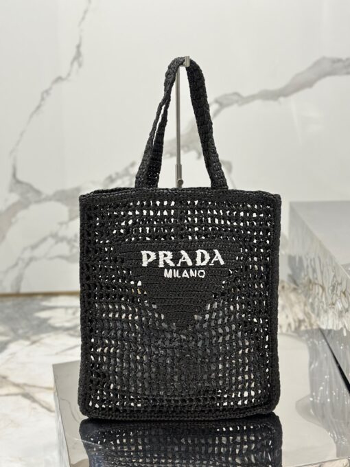 PRADA Crochet Tote Bag. Elevate your style with Prada's signature tote bag. This tote bag is the perfect addition to any summer wardrobe! Adorned with Prada's iconic triangle logo and embroidered lettering, its soft, deconstructed design is made with a light and natural raffia-effect yarn. It's sure to add an elevated touch to your ensemble. | CRIS&COCO Authentic Quality Designer Bags and Luxury Accessories