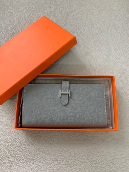 HERMÈS Béarn Wallet: Where Elegance Meets Functionality, Inspired by the Heart of France's South-West. The Béarn pays homage to the enchanting South-West region of France and stands as a distinguished member of a collection that honors various distinctive French regions. This wallet or card holder boasts an elegantly sleek design and is thoughtfully equipped with multiple compartments tailored for organizing credit cards, coins, and bills with ease. Upon closure, a supple leather flap gracefully glides into an iconic "H" shaped clasp, elevating it to a timeless classic. It presents a generous array of leather types and colors, allowing one to harmonize effortlessly with the latest trends in style.