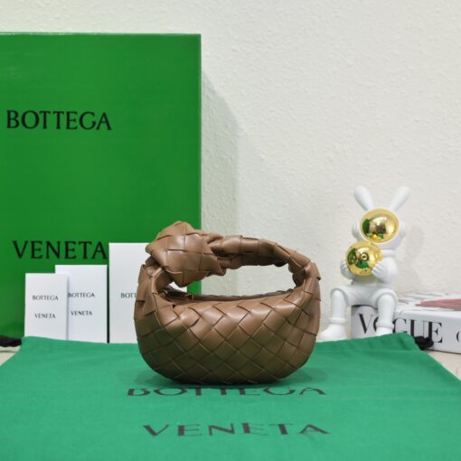 BOTTEGA VENETA Mini Jodie. Mini Marvel: Elevate Your Essentials. Introducing the BV Mini Jodie by Daniel Lee, a captivating embodiment of the mini bag trend infused with a beautiful minimalist essence. True to the distinctive allure of the Jodie collection, this rendition showcases the iconic Intrecciato weave and the signature knot embellishment. Delicately compact, it effortlessly nestles under your arm like a charming baguette bag yet offers ample space for essentials such as your phone, cards, and keys. Despite its diminutive size, this mini bag radiates a vibrant aura through various lively hues, ensuring it leaves a memorable impression.