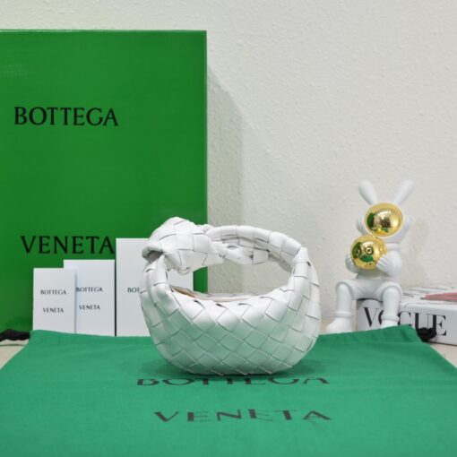 BOTTEGA VENETA Mini Jodie. Mini Marvel: Elevate Your Essentials. Introducing the BV Mini Jodie by Daniel Lee, a captivating embodiment of the mini bag trend infused with a beautiful minimalist essence. True to the distinctive allure of the Jodie collection, this rendition showcases the iconic Intrecciato weave and the signature knot embellishment. Delicately compact, it effortlessly nestles under your arm like a charming baguette bag yet offers ample space for essentials such as your phone, cards, and keys. Despite its diminutive size, this mini bag radiates a vibrant aura through various lively hues, ensuring it leaves a memorable impression.