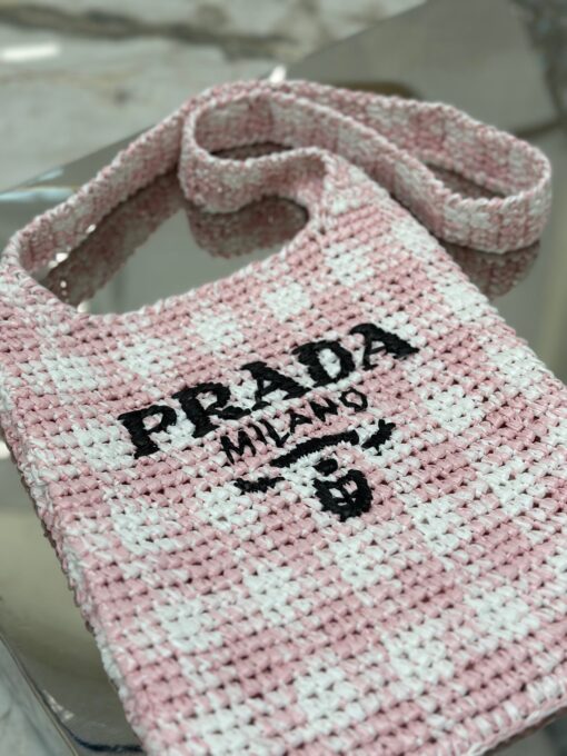 PRADA Crochet Bag- where refined logos meet natural raffia-inspired beauty. Introducing a beautifully crafted tote bag, featuring a gentle, deconstructed design, elegantly crafted from raffia-effect yarn. This lightweight and natural material exudes a delightful summery vibe. The front adorns a sleek enameled metal triangle logo and delicately embroidered lettering logo, engaging in a captivating and harmonious aesthetic conversation.