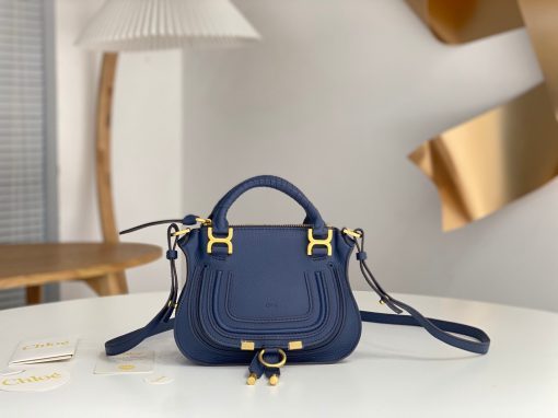 CHLOÉ Marcie Mini Double Carry Bag: Elegance in Miniature. Introducing a charming, petite rendition of the iconic Marcie handbag, this mini double carry bag exudes elegance with its meticulous craftsmanship in grained calfskin. Its clean, sleek lines and gracefully contoured design elevate the relaxed, slouchy silhouette, while the hand-wrapped leather handles impart an artisanal touch. The addition of metallic buckles bestows a polished and refined finish to this exquisite creation. Equipped with both double handles and a long, detachable shoulder strap, this mini bag epitomizes versatility, making it a must-have accessory for any occasion.