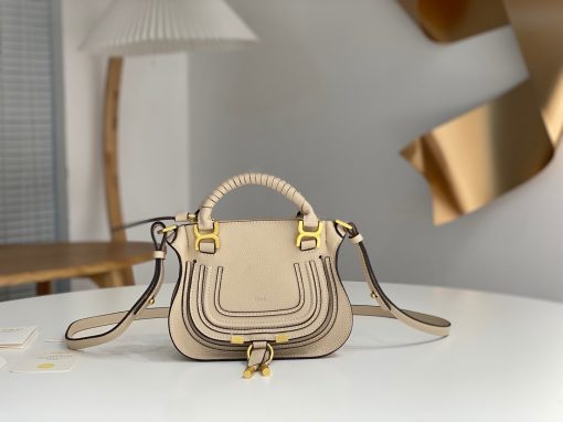 CHLOÉ Marcie Mini Double Carry Bag: Elegance in Miniature. Introducing a charming, petite rendition of the iconic Marcie handbag, this mini double carry bag exudes elegance with its meticulous craftsmanship in grained calfskin. Its clean, sleek lines and gracefully contoured design elevate the relaxed, slouchy silhouette, while the hand-wrapped leather handles impart an artisanal touch. The addition of metallic buckles bestows a polished and refined finish to this exquisite creation. Equipped with both double handles and a long, detachable shoulder strap, this mini bag epitomizes versatility, making it a must-have accessory for any occasion.