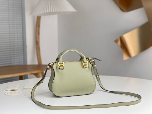 CHLOÉ Marcie Mini Double Carry Bag: Elegance in Miniature. Introducing a charming, petite rendition of the iconic Marcie handbag, this mini double carry bag exudes elegance with its meticulous craftsmanship in grained calfskin. Its clean, sleek lines and gracefully contoured design elevate the relaxed, slouchy silhouette, while the hand-wrapped leather handles impart an artisanal touch. The addition of metallic buckles bestows a polished and refined finish to this exquisite creation. Equipped with both double handles and a long, detachable shoulder strap, this mini bag epitomizes versatility, making it a must-have accessory for any occasion.