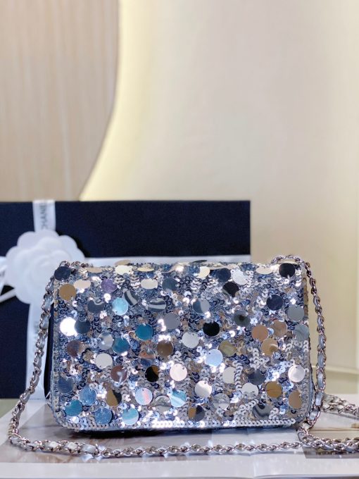 CHANEL Mini Flap Bag In Sequins. Authentic quality luxury bag comes with authenticity card, dust bag and gift bag. Sequins and Sophistication: Elevate Your Style with Timeless Elegance. This exquisite flap bag showcases a combination of small and large sequins meticulously arranged to cover the entirety of its surface. The sophisticated design includes refined leather shoulder straps adorned with polished chain links, as well as a chic CC turn lock. Opening the bag reveals a spacious leather interior that can accommodate all your essential items for both day and evening occasions while maintaining its timeless allure.