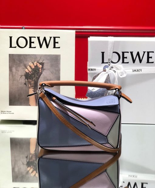 LOEWE Mini Puzzle Bag. Authentic quality luxury bag crafted in genuine leather comes with authenticity card, dust bag and gift bag. Cuboid Shape Meets Precise Craftsmanship The debut bag for *OEWE by Creative Director Jonathan Anderson is the Puzzle bag. With its cuboid shape and precise cutting technique, it boasts distinctive geometric lines. This particular mini version has been expertly crafted using contrasting calfskins.