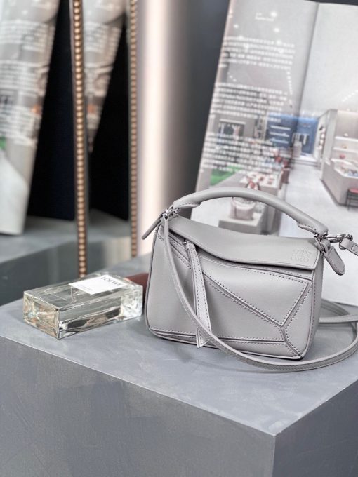LOEWE Mini Puzzle Bag. Original Quality Bag including gift box, care book, dust bag, authenticity card. The Puzzle bag is the debut bag for LOEWE by Creative Director Jonathan Anderson. A cuboid shape and precise cutting technique create Puzzle’s distinctive geometric lines. This mini version is crafted in contrasting calfskins.