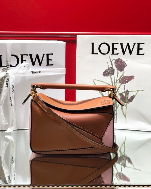 LOEWE Mini Puzzle Bag. Authentic quality luxury bag crafted in genuine leather comes with authenticity card, dust bag and gift bag. Cuboid Shape Meets Precise Craftsmanship The debut bag for *OEWE by Creative Director Jonathan Anderson is the Puzzle bag. With its cuboid shape and precise cutting technique, it boasts distinctive geometric lines. This particular mini version has been expertly crafted using contrasting calfskins.