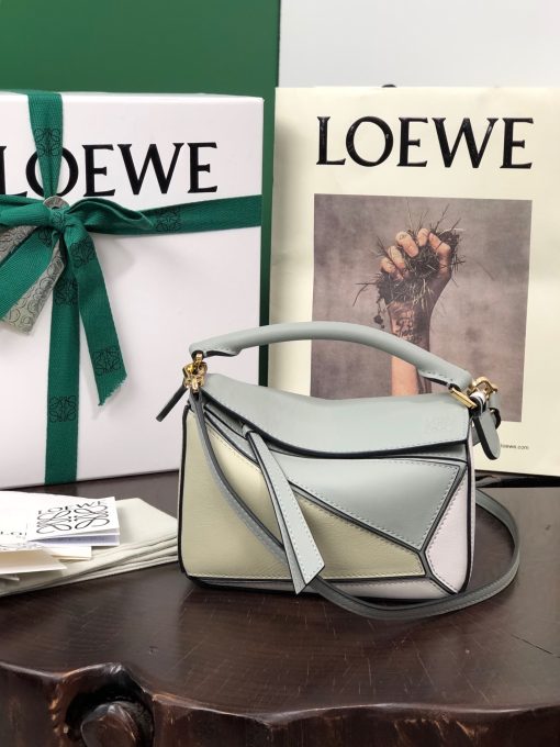 LOEWE Mini Puzzle Bag. Authentic quality luxury bag crafted in genuine leather comes with authenticity card, dust bag and gift bag. Cuboid Shape Meets Precise Craftsmanship The debut bag for *OEWE by Creative Director Jonathan Anderson is the Puzzle bag. With its cuboid shape and precise cutting technique, it boasts distinctive geometric lines. This particular mini version has been expertly crafted using contrasting calfskins.