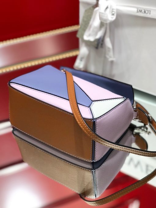 LOEWE Mini Puzzle Bag. Authentic quality luxury bag crafted in genuine leather comes with authenticity card, dust bag and gift bag. Cuboid Shape Meets Precise Craftsmanship The debut bag for *OEWE by Creative Director Jonathan Anderson is the Puzzle bag. With its cuboid shape and precise cutting technique, it boasts distinctive geometric lines. This particular mini version has been expertly crafted using contrasting calfskins.