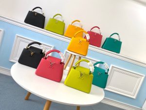 LOUIS VUITTON Capucines Mini. Authentic quality luxury bag crafted in genuine leather comes with authenticity card, dust bag and gift bag. Captivatingly vibrant. Effortlessly sophisticated. Crafted from vibrant Taurillon leather, the Capucines Mini handbag exudes an exquisite charm. Its striking color palette is tastefully enhanced by the understated metal handle rings. Just like every Capucines, this Mini version can be effortlessly carried with the flap out, adding an air of effortless elegance, or tucked inside to showcase the iconic LV Initials. - KRIS + KIKO LOUIS VUITTON Capucines Mini. Original Quality Bag including gift box, literature, dust bag, authenticity card. Fashioned from vibrantly colored Taurillon leather, the Capucines Mini handbag pops. The fresh new colorway is perfectly complemented by the discreet metal handle rings. Like all Capucines, the Mini can be carried with the flap out for simple sophistication or tucked inside to feature the LV Initials.