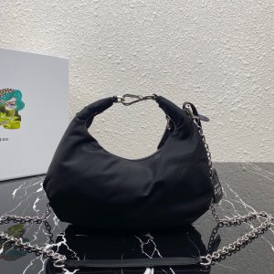 PRADA Re-Edition 2006 Nylon Hobo. Authentic quality luxury bag crafted in genuine leather comes with authenticity card, dust bag and gift bag. Classic Silhouette, Modern Functionality, Unforgettable Style. Crafted from the renowned and recognizable nylon, a fabric emblematic of the brand, this shoulder bag effortlessly melds a timeless design with contemporary and practical elements. Enhancing its appeal are the detachable chain shoulder strap and the Re-Edition leather keyring, further elevating this accessory. - KRIS + KIKO PRADA Re-Edition 2006 Nylon Hobo. Authentic quality luxury bag crafted in genuine leather comes with authenticity card, dust bag and gift bag. Classic Silhouette, Modern Functionality, Unforgettable Style. Crafted from the renowned and recognizable nylon, a fabric emblematic of the brand, this shoulder bag effortlessly melds a timeless design with contemporary and practical elements. Enhancing its appeal are the detachable chain shoulder strap and the Re-Edition leather keyring, further elevating this accessory.