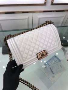 CHANEL Boy Quilted Leather Flap Bag. Authentic quality luxury bag crafted in genuine leather comes with authenticity card, dust bag and gift bag. Unveil Elegance: Elevate Your Style with CHANEL's Iconic Quilted Flap Bag. Elegantly designed, this exceptional CHANEL Boy quilted flap bag boasts a striking chain-link strap with a comfortable shoulder pad, a distinctive CC Boy logo push-lock closure, and exquisite antiqued hardware accents. Opening the push-lock closure reveals a luxurious black fabric-lined interior, complete with convenient side zip and slip pockets, perfect for securely organizing one's daily necessities. - KRIS + KIKO CHANEL Boy Quilted Leather Flap Bag. Original Quality Bag including gift box, literature, dust bag, authenticity card. This stand-out, enviable CHANEL Boy quilted flap bag features a chunky chain-link strap with shoulder pad, CC Boy logo push-lock closure, and antiqued hardware accents. Its push-lock closure opens to a black fabric-lined interior with side zip and slip pockets to secure daily essentials.