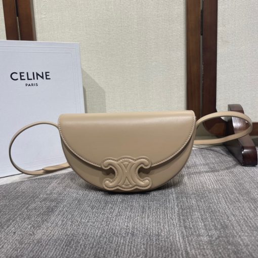 CELINE Besace Cuir Triomphe. Authentic quality luxury bag crafted in genuine leather comes with authenticity card, dust bag and gift bag. Revamp your style with our half-moon shape bags, featuring an oversized Triomphe logo and a roomy interior for all your essentials.. Presented in the current trendsetting half-moon shape, our significantly wider format measures 23 cm from tip to tip. Each bag effortlessly opens with a snap button closure, revealing a spacious interior compartment and a convenient flat inner pocket. One notable feature of the bag is the oversized Triomphe logo, showcased with contrasting Tan leather against the Triomphe Canvas. Tonal stitching along the edges adds a refined touch. To achieve a stylish monochrome effect, choose the Ice Blue and Tan option, where the logos are elegantly matched in color.