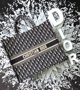 DIOR Book Tote DIOR Oblique Canvas Bag. Authentic quality luxury bag crafted in genuine leather comes with authenticity card, dust bag and gift bag. Inspired by Heritage, Designed for the Future. Inspired by a beautiful drawing created by Marc Bohan in 1967, Maria Grazia Chiuri delved into the esteemed Dior House archives to unveil the magnificent Dior Book Tote as part of the brand's exquisite Spring/Summer 2018 collection. - KRIS + KIKO DIOR Book Tote DIOR Oblique Canvas Bag. High Quality Bag. Original quality DIOR Oblique Jacquard. DIOR Sales Box and Dust Bag. Booklet, Authenticity Card, Payment Slip. Introduced for the brand’s Spring/Summer 2018 collection, Maria Grazia Chiuri immersed herself in Dior House archives to find inspiration from a drawing produced by Marc Bohan in 1967 to create the Dior Book Tote.