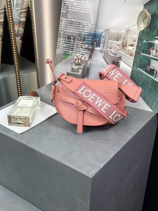 LOEWE Mini Gate Dual Bag. Authentic quality luxury bag crafted in genuine leather comes with authenticity card, dust bag and gift bag. Discover the Art of Leather: Elevate your Style. Exquisitely designed with utmost precision, the Mini Gate Dual showcases LOEWE's unparalleled expertise in leatherwork, enveloped in supple calfskin. Its distinctive features include a meticulously saddle-stitched knotted leather strap and a side-latched metal pin, from which the bag derives its name. Moreover, this miniature rendition is equipped with a removable shoulder strap, also rendered in calfskin, embellished with a repeated LOEWE pattern crafted in jacquard.
