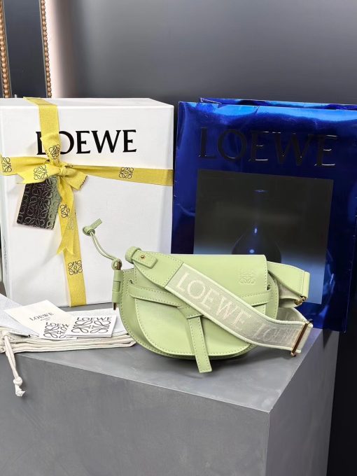 LOEWE Mini Gate Dual Bag. Authentic quality luxury bag crafted in genuine leather comes with authenticity card, dust bag and gift bag. Discover the Art of Leather: Elevate your Style. Exquisitely designed with utmost precision, the Mini Gate Dual showcases LOEWE's unparalleled expertise in leatherwork, enveloped in supple calfskin. Its distinctive features include a meticulously saddle-stitched knotted leather strap and a side-latched metal pin, from which the bag derives its name. Moreover, this miniature rendition is equipped with a removable shoulder strap, also rendered in calfskin, embellished with a repeated LOEWE pattern crafted in jacquard.