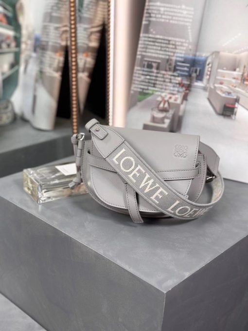 LOEWE Mini Gate Dual Bag. Authentic quality luxury bag crafted in genuine leather comes with authenticity card, dust bag and gift bag. Discover the Art of Leather: Elevate your Style. Exquisitely designed with utmost precision, the Mini Gate Dual showcases LOEWE's unparalleled expertise in leatherwork, enveloped in supple calfskin. Its distinctive features include a meticulously saddle-stitched knotted leather strap and a side-latched metal pin, from which the bag derives its name. Moreover, this miniature rendition is equipped with a removable shoulder strap, also rendered in calfskin, embellished with a repeated LOEWE pattern crafted in jacquard.