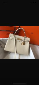 HERMÈS 'Kelly' Sellier Calf Leather Shoulder Bag. Authentic quality luxury bag crafted in genuine leather comes with authenticity card, dust bag and gift bag. Timeless Elegance, From Grace to Iconography. In 1930, a century after HERMÈS first opened its saddle-making workshops, Robert Dumas introduced a charming new creation for women - a small bag with straps. This bag featured a trapezoid shape, two triangular gussets, a sculpted flap, a handle, and ample storage space. Its design was simple and practical, tailored specifically for independent and energetic women. The bag with straps quickly became iconic for HERMÈS, embodying both desirability and discreetness. Then, in 1956, a significant moment occurred. Grace Kelly, the renowned Hollywood star turned princess, artfully concealed her baby bump behind her HERMÈS bag with straps. This image spread worldwide, instantly catapulting the bag into the limelight. And thus, the Kelly bag was born. - KRIS + KIKO HERMÈS 'Kelly' Sellier Calf Leather Shoulder Bag. Original Quality Bag. Gold-metal toned Hardware. HERMÈS Sales Box and Dust Bag. Booklet, Authenticity Card, Payment Slip. Lock, key clochette, and two keys are included. 1930, a century after the house of HERMÈS opened the doors of its saddle-making workshops, Robert Dumas created a small bag with straps for ladies. It had a trapezoid shape, two triangular gussets, a sculpted flap, a handle, and good storage space. Nothing fancy, just a neat, plain, functional bag intended for independent, energetic women. The ladies’ bag with straps was an emblematic HERMÈS design: both highly desirable yet anonymous. 1956, Grace Kelly, the Hollywood star who became a princess, hides her baby bump behind her Hermès bag with straps. The picture goes around the world, and the bag is instantly crowned. The Kelly bag is born.