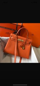 HERMÈS 'Kelly' Sellier Calf Leather Shoulder Bag. Original Quality Bag. Gold-metal toned Hardware. HERMÈS Sales Box and Dust Bag. Booklet, Authenticity Card, Payment Slip. Lock, key clochette, and two keys are included. 1930, a century after the house of HERMÈS opened the doors of its saddle-making workshops, Robert Dumas created a small bag with straps for ladies. It had a trapezoid shape, two triangular gussets, a sculpted flap, a handle, and good storage space. Nothing fancy, just a neat, plain, functional bag intended for independent, energetic women. The ladies’ bag with straps was an emblematic HERMÈS design: both highly desirable yet anonymous. 1956, Grace Kelly, the Hollywood star who became a princess, hides her baby bump behind her Hermès bag with straps. The picture goes around the world, and the bag is instantly crowned. The Kelly bag is born.