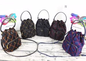 PRADA Quilted Bucket Bag. Authentic quality luxury bag crafted in genuine leather comes with authenticity card, dust bag and gift bag. Elevating Style with Quilted Luxury. Introducing the exquisite PRADA nylon bucket bag, featuring tessuto-impunturato quilted topstitching for a luxurious touch. Designed with a sleek leather top handle, this bag showcases a convenient drawstring top closure for easy access. It also includes a detachable shoulder strap, allowing for versatile carrying options. The front zip pocket, adorned with an elegant logo plate, adds a chic element to this stunning bag. - KRIS + KIKO CRIS&COCO Authentic Quality bags and Accessories