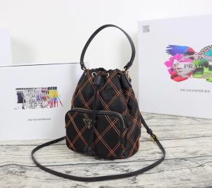 PRADA Quilted Bucket Bag. Authentic quality luxury bag crafted in genuine leather comes with authenticity card, dust bag and gift bag. Elevating Style with Quilted Luxury. Introducing the exquisite PRADA nylon bucket bag, featuring tessuto-impunturato quilted topstitching for a luxurious touch. Designed with a sleek leather top handle, this bag showcases a convenient drawstring top closure for easy access. It also includes a detachable shoulder strap, allowing for versatile carrying options. The front zip pocket, adorned with an elegant logo plate, adds a chic element to this stunning bag. - KRIS + KIKO PRADA Quilted Bucket Bag. Original Quality Bag including gift box, care book, dust bag, authenticity card. PRADA nylon bucket bag with tessuto-impunturato quilted topstitching. Leather top handle. Drawstring top. Detachable Shoulder Strap. Front Zip Pocket with logo plate.