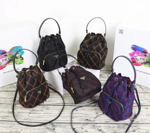 PRADA Quilted Bucket Bag. Authentic quality luxury bag crafted in genuine leather comes with authenticity card, dust bag and gift bag. Elevating Style with Quilted Luxury. Introducing the exquisite PRADA nylon bucket bag, featuring tessuto-impunturato quilted topstitching for a luxurious touch. Designed with a sleek leather top handle, this bag showcases a convenient drawstring top closure for easy access. It also includes a detachable shoulder strap, allowing for versatile carrying options. The front zip pocket, adorned with an elegant logo plate, adds a chic element to this stunning bag. - KRIS + KIKO PRADA Quilted Bucket Bag. Original Quality Bag including gift box, care book, dust bag, authenticity card. PRADA nylon bucket bag with tessuto-impunturato quilted topstitching. Leather top handle. Drawstring top. Detachable Shoulder Strap. Front Zip Pocket with logo plate.