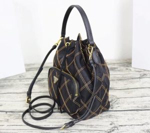 PRADA Quilted Bucket Bag. Authentic quality luxury bag crafted in genuine leather comes with authenticity card, dust bag and gift bag. Elevating Style with Quilted Luxury. Introducing the exquisite PRADA nylon bucket bag, featuring tessuto-impunturato quilted topstitching for a luxurious touch. Designed with a sleek leather top handle, this bag showcases a convenient drawstring top closure for easy access. It also includes a detachable shoulder strap, allowing for versatile carrying options. The front zip pocket, adorned with an elegant logo plate, adds a chic element to this stunning bag. - KRIS + KIKO PRADA Quilted Bucket Bag. Authentic quality luxury bag crafted in genuine leather comes with authenticity card, dust bag and gift bag. Elevating Style with Quilted Luxury. Introducing the exquisite PRADA nylon bucket bag, featuring tessuto-impunturato quilted topstitching for a luxurious touch. Designed with a sleek leather top handle, this bag showcases a convenient drawstring top closure for easy access. It also includes a detachable shoulder strap, allowing for versatile carrying options. The front zip pocket, adorned with an elegant logo plate, adds a chic element to this stunning bag.