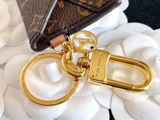LOUIS VUITTON Kirigami Pouch Bag Charm & Key Holder. Authentic quality luxury accessory crafted in genuine leather comes with authenticity card, dust bag and gift bag. Exquisite Practicality, Perfected Elegance. The pouch bag charm and key holder effortlessly combine practicality and elegance. The design showcases the iconic Monogram canvas, adding a touch of versatility. With a functional pouch that opens through a convenient snap button, every detail is flawlessly crafted. Inside, a luxurious suede lining awaits, complemented by House emblems like the LV Circle charm and signature engraving, adding a distinctive touch.