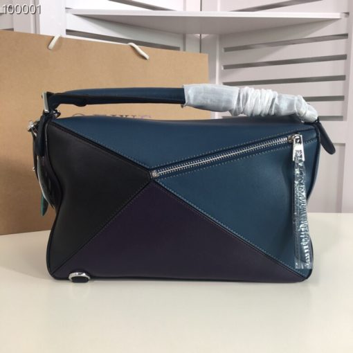 LOEWE 'Puzzle' Shoulder Bag. Authentic quality luxury bag crafted in genuine leather comes with authenticity card, dust bag and gift bag. Unleash the Iconic Cuboid Innovation. The debut bag by Jonathan Anderson has captured the essence of LOEWE and achieved iconic status. This innovative creation showcases a cuboid shape, offering both a remarkable tactile experience and exceptional practicality. The bag's unique volume is achieved through precise cutting, enabling it to be worn in five distinctive styles - from a chic shoulder bag to an elegant clutch - and can even be folded flat for convenient storage. Notable features include the luxurious calfskin craftsmanship, stylish black hand-painted edges, herringbone-patterned cotton-canvas lining, and two internal slip compartments for organized storage. Additionally, a convenient exterior zip back pocket and an embossed anagram add to the bag's functionality and charm. To ensure optimal comfort, the bag also offers a removable adjustable shoulder strap, allowing for a personalized fit.