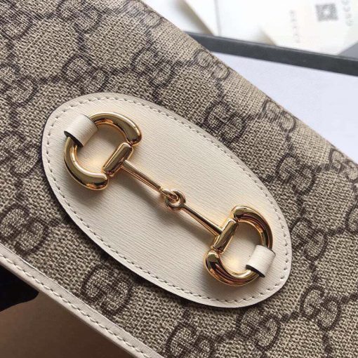 GUCCI 1955 GG Supreme Horsebit Wallet On Chain. Authentic quality luxury bag crafted in genuine leather comes with authenticity card, dust bag and gift bag. Unlock the essence of timeless elegance. Introducing the chain wallet from Gucci's esteemed Horsebit 1955 accessories collection, crafted with GG Supreme canvas and leather. This exquisite piece showcases the iconic double ring and bar design found in their esteemed Handbags line. The wallet's sleek snap-closure shape reveals numerous card slots and pockets, offering practicality alongside style. Furthermore, it boasts a detachable chain strap, adding versatility to its elegant design.