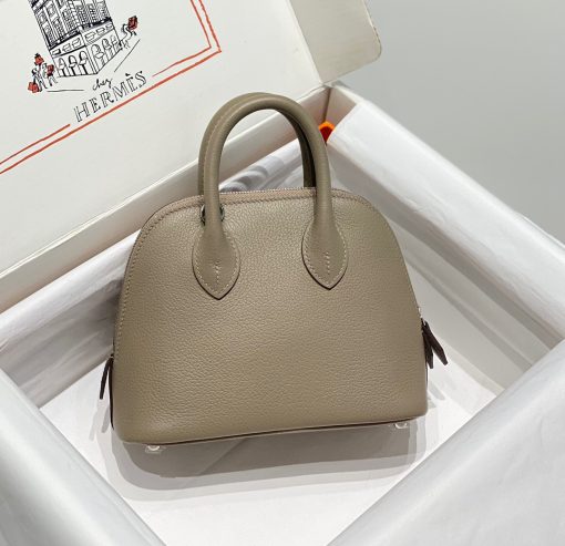 HERMÈS Bolide 1923 Mini. Authentic quality luxury bag crafted in genuine leather comes with authenticity card, dust bag and gift bag. Timeless Elegance, Unparalleled Convenience: The Bolide Bag – A Journey in Every Stitch. Created in 1923 with the discerning needs of elite drivers and seasoned long-distance travelers in mind, this globe-trotting bag effortlessly finds its place within any automobile trunk. Its iconic round-angled shape owes its origins to the zip fastener, a novel invention introduced to France by Émile Hermès in the late 1910s, and this innovative feature enables swift access to its contents. The Bolide bag is available in various sizes, including a travel-sized version, and a range of handbag options, offering both style and functionality to its fortunate owners.
