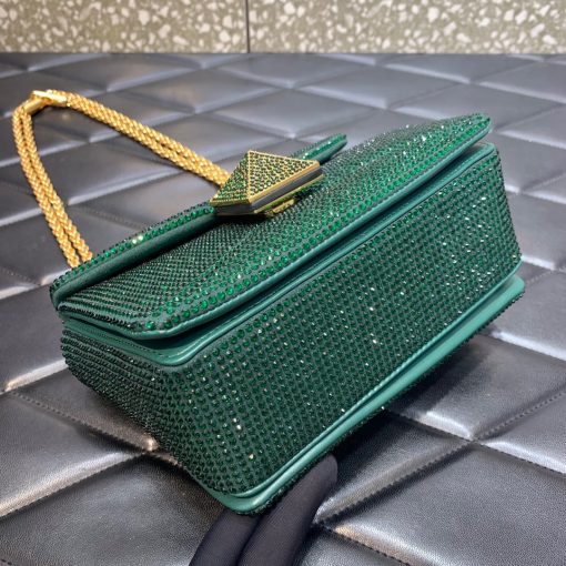 VALENTINO One Stud Small Bag. Authentic quality luxury bag crafted in genuine leather comes with authenticity card, dust bag and gift bag. Sparkle and Shine with Jeweled Design. This One Stud model by VALENTINO Garavani showcases a stunning jeweled design. Its shiny color is adorned with dazzling crystals, creating a truly eye-catching accessory. The bag is elegantly trimmed with tonal suede and crafted into a small silhouette with a flap top and magnet closure. Inside, you'll find a single compartment with handy pockets for organization. The sliding chain strap adds versatility, allowing you to wear the bag on your shoulder. To complete the luxurious look, the front is adorned with the iconic Maxi Stud decoration.