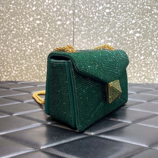 VALENTINO One Stud Small Bag. Authentic quality luxury bag crafted in genuine leather comes with authenticity card, dust bag and gift bag. Sparkle and Shine with Jeweled Design. This One Stud model by VALENTINO Garavani showcases a stunning jeweled design. Its shiny color is adorned with dazzling crystals, creating a truly eye-catching accessory. The bag is elegantly trimmed with tonal suede and crafted into a small silhouette with a flap top and magnet closure. Inside, you'll find a single compartment with handy pockets for organization. The sliding chain strap adds versatility, allowing you to wear the bag on your shoulder. To complete the luxurious look, the front is adorned with the iconic Maxi Stud decoration.
