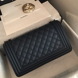 CHANEL Chevron Quilted Leather Flap Bag. Authentic quality luxury bag crafted in genuine leather comes with authenticity card, dust bag and gift bag. A love story in every stitch. The Chanel Boy Flap Bag Quilted is an exquisite creation by the renowned Karl Lagerfeld, paying homage to Gabrielle Chanel's beloved Boy Capel. This iconic design truly represents every woman's ultimate aspiration. Meticulously crafted from high-quality calfskin leather, this bag showcases Chanel's distinctive chevron quilting, complemented by a striking chunky chain link strap adorned with a leather shoulder pad and elegant metal-tone hardware accents. Opening with a captivating CC Boy logo closure, its fabric-lined interior includes a convenient slip pocket, ideal for organizing daily essentials. With its undeniable allure, this sought-after accessory is a luxurious must-have.