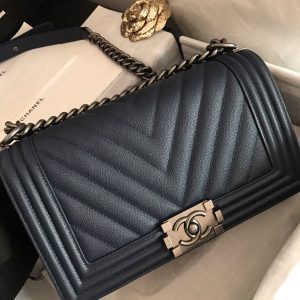 CHANEL Chevron Quilted Leather Flap Bag. Authentic quality luxury bag crafted in genuine leather comes with authenticity card, dust bag and gift bag. A love story in every stitch. The Chanel Boy Flap Bag Quilted is an exquisite creation by the renowned Karl Lagerfeld, paying homage to Gabrielle Chanel's beloved Boy Capel. This iconic design truly represents every woman's ultimate aspiration. Meticulously crafted from high-quality calfskin leather, this bag showcases Chanel's distinctive chevron quilting, complemented by a striking chunky chain link strap adorned with a leather shoulder pad and elegant metal-tone hardware accents. Opening with a captivating CC Boy logo closure, its fabric-lined interior includes a convenient slip pocket, ideal for organizing daily essentials. With its undeniable allure, this sought-after accessory is a luxurious must-have. - KRIS + KIKO CHANEL Chevron Quilted Leather Flap Bag. Original high quality bag. Authentic design. Original quality printed dust bag and sales box. Created by Karl Lagerfeld, the iconic design owes its name to Gabrielle Chanel's first love, Boy Capel. This Chanel Boy Flap Bag Quilted is every woman's dream. Crafted from calfskin leather, the bag features Chanel's signature chevron quilting, chunky chain link strap with leather shoulder pad, and metal-tone hardware accents. Its CC Boy logo closure opens to a fabric-lined interior with slip pocket perfect for daily essentials. A sought-after, luxurious accessory.
