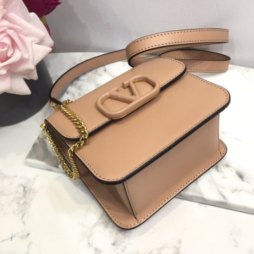 VALENTINO VSling Mini Leather Shoulder Bag. Authentic quality luxury bag crafted in genuine leather comes with authenticity card, dust bag and gift bag. Elegance Meets Functionality. VALENTINO's SS20 accessories collection showcases their new V Ring logo, which has left us completely captivated. Pierpaolo Picciolil's attention to clean lines and thoughtful details is evident in this exquisite orange leather V-logo bag. The adjustable cross-body strap adds functionality to its elegance, while the iconic logo plaque graces the front flap. Inside, a black leather interior with a convenient slip pocket awaits. For a chic ensemble, pair it with a blouse tucked into a midi skirt and wear it gracefully over your shoulder.