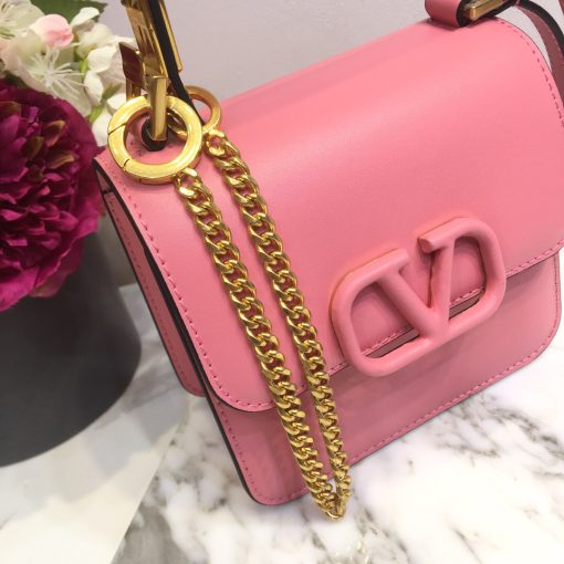 VALENTINO VSling Mini Leather Shoulder Bag. Authentic quality luxury bag crafted in genuine leather comes with authenticity card, dust bag and gift bag. Elegance Meets Functionality. VALENTINO's SS20 accessories collection showcases their new V Ring logo, which has left us completely captivated. Pierpaolo Picciolil's attention to clean lines and thoughtful details is evident in this exquisite orange leather V-logo bag. The adjustable cross-body strap adds functionality to its elegance, while the iconic logo plaque graces the front flap. Inside, a black leather interior with a convenient slip pocket awaits. For a chic ensemble, pair it with a blouse tucked into a midi skirt and wear it gracefully over your shoulder.