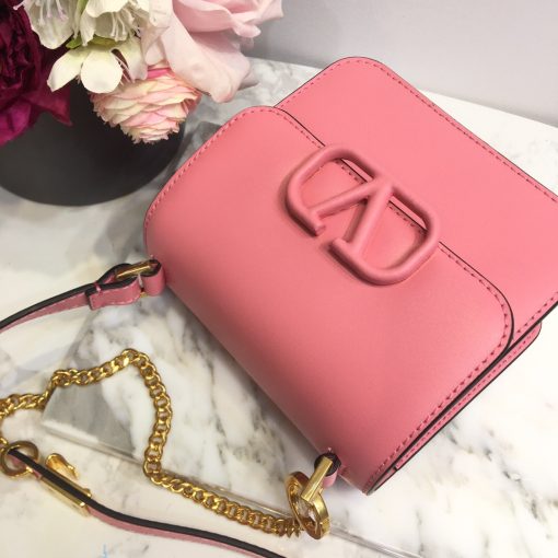 VALENTINO VSling Mini Leather Shoulder Bag. Authentic quality luxury bag crafted in genuine leather comes with authenticity card, dust bag and gift bag. Elegance Meets Functionality. VALENTINO's SS20 accessories collection showcases their new V Ring logo, which has left us completely captivated. Pierpaolo Picciolil's attention to clean lines and thoughtful details is evident in this exquisite orange leather V-logo bag. The adjustable cross-body strap adds functionality to its elegance, while the iconic logo plaque graces the front flap. Inside, a black leather interior with a convenient slip pocket awaits. For a chic ensemble, pair it with a blouse tucked into a midi skirt and wear it gracefully over your shoulder.